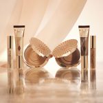 Foundation in a sleek gold-coloured tube with a concealer in a glass tube and gold-coloured lid, and dark brown cream bronzer compact in gold-coloured packaging.