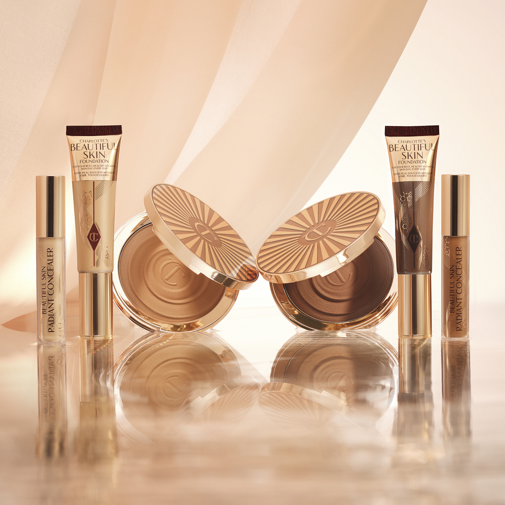 Foundation in a sleek gold-coloured tube with a concealer in a glass tube and gold-coloured lid, and dark brown cream bronzer compact in gold-coloured packaging.
