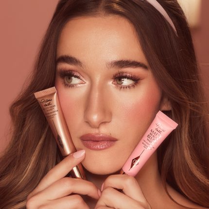 A fair skin model holding and wearing a liquid blush and liquid highligher