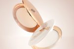 Two, open, setting powder compacts with mirrored-lids and white and gold-coloured packaging.