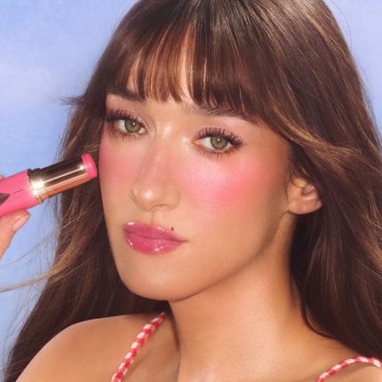 Medium model wearing and holding pink blush shade.