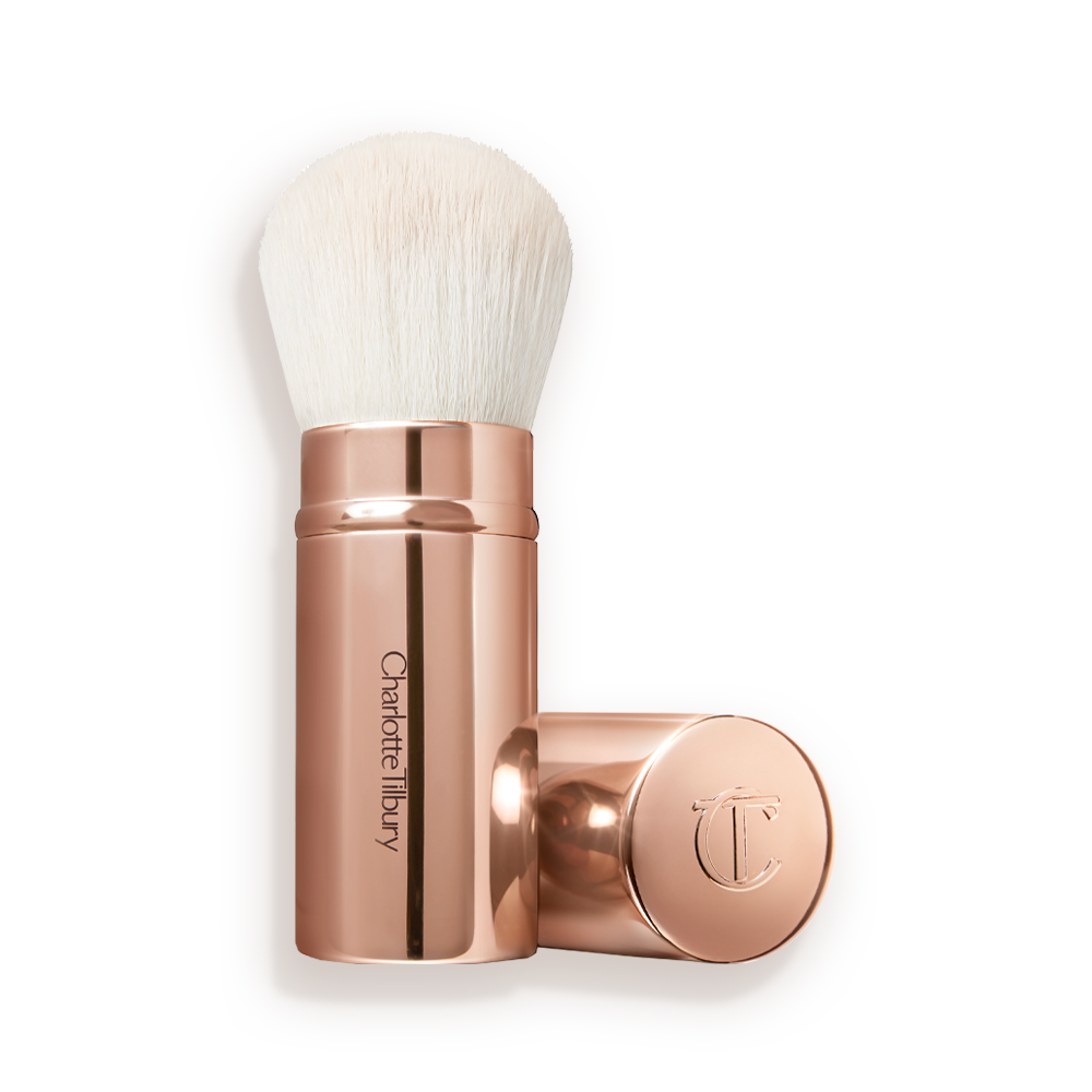 Airbrush_Brush_Open_Packshot A face blending brush with white bristles in rose gold packaging with the cap beside it.