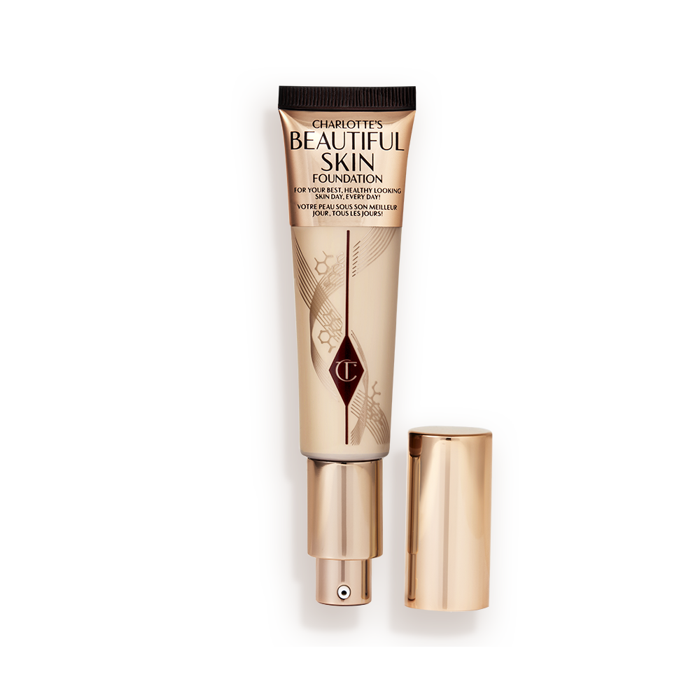 BEAUTIFUL_SKIN_FOUNDATION_SHADE_2_NEUTRAL_LID_SIDE__1_ An open foundation wand in gold packaging with a pump dispenser and a medium-beige-coloured body to show the shade of the foundation inside.