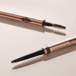 Close-up of a dual-ended eyebrow pencil and spoolie brush stick with gold-coloured sleek packaging.