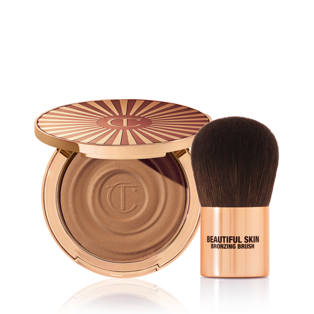 BS-Bronzer-Brush-Bundle An open cream bronzer compact with gold-coloured packaging with a bronzer brush with soft,d ark-brown-coloured bristles and a golden-coloured handle.