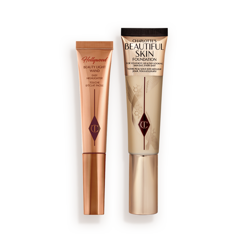CHARLOTTE-S_BEAUTIFUL_SKIN_GLOW_KIT Highlighter wand in light gold-coloured packaging with a foundation wand in gold packaging with a ashy brown-beige-coloured body to show the shade of the foundation inside, and a gold-coloured lid.