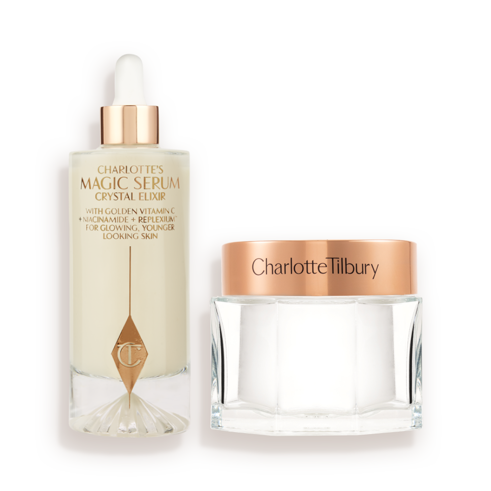 CHARLOTTEa__S_SUPERSIZED_MAGIC_SKIN_DUO A large serum in a glass bottle with a golden and white-coloured dropper lid and pearly-white face cream in a glass jar with a rose-gold-coloured lid.