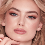Zoomed in view of a blonde, fair skin model, wearing glowy, nude-pink makeup.