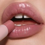 Lips close-up of a light-tone model wearing a moisturising lipstick lip balm in a nude pink berry shade.