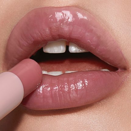 Lips close-up of a light-tone model wearing a moisturising lipstick lip balm in a nude pink berry shade.