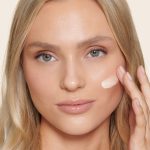 Model applying Unisex Healthy Glow tinted moisturiser for a minimal makeup look
