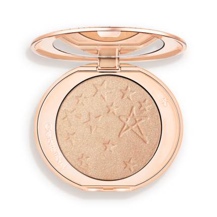 An open highlighter powder compact with a mirrored lid, in a shimmery champagne shade.