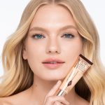 Light-tone blonde model wearing glowy, skin-like foundation with a satin finish with nude lipstick and subtle eye makeup.
