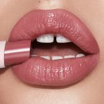 Lips close-up of a light-tone model wearing a moisturising lipstick balm in a nude pink shade.