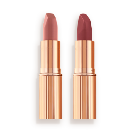 Two matte lipsticks, one a nude pink and the other a berry-rose shade in golden, metallic tubes with their lids removed. 