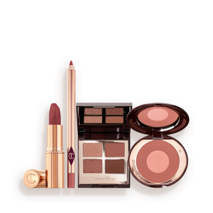 A makeup kit containing a two-tone pink and rose gold blush, a berry and pink quad eyeshadow palette, a nude-pink lip liner pencil, and rose-pink lipstick.