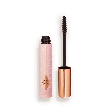 Mascara in a pink-coloured tube with its gold-coloured lid with a black applicator next to it.