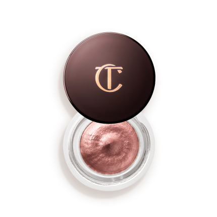 Cream eyeshadow in an open glass pot in a nude pink shade with fine shimmer, with the lid placed next to it.