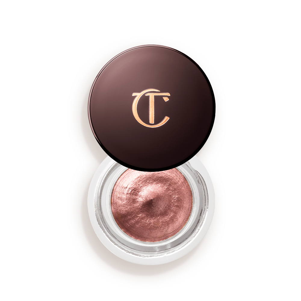 Pillow-Talk-Eyes-to-Mesmerise-Packshot-Top Cream eyeshadow in an open glass pot in a nude pink shade with fine shimmer, with the lid placed next to it.