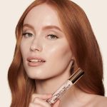 Fair-tone model with green eyes wearing a radiant, concealer that brightens, covers blemishes, and makes her skin look fresh along with nude lip gloss and subtle eye makeup.