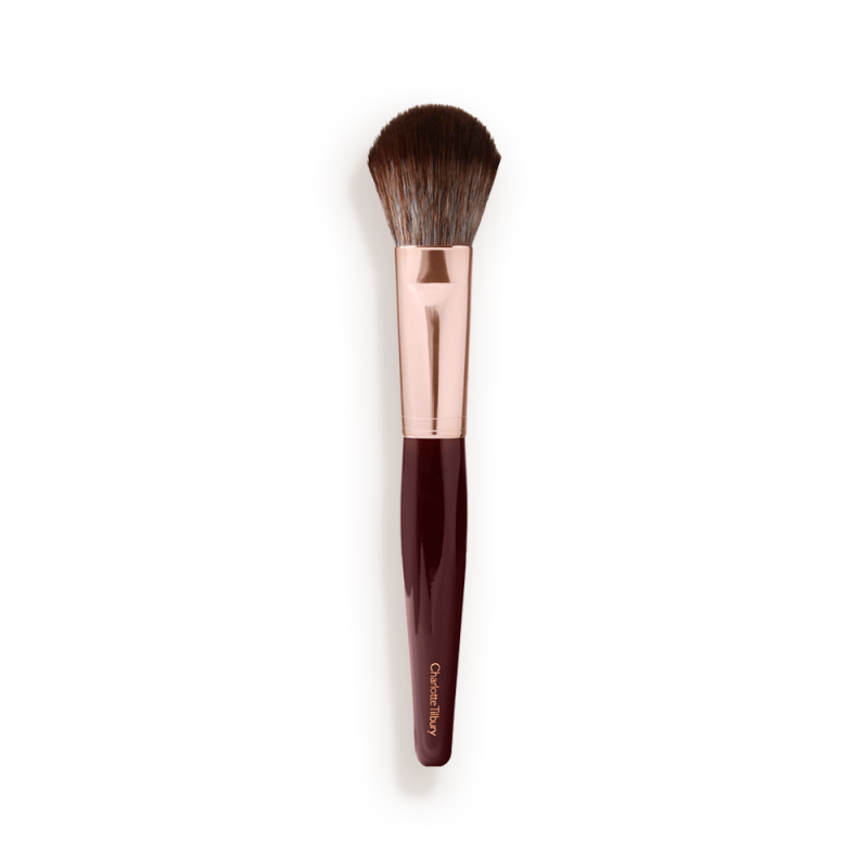 A bronzer and blush brush with soft bristles and rose gold and dark crimson handle.