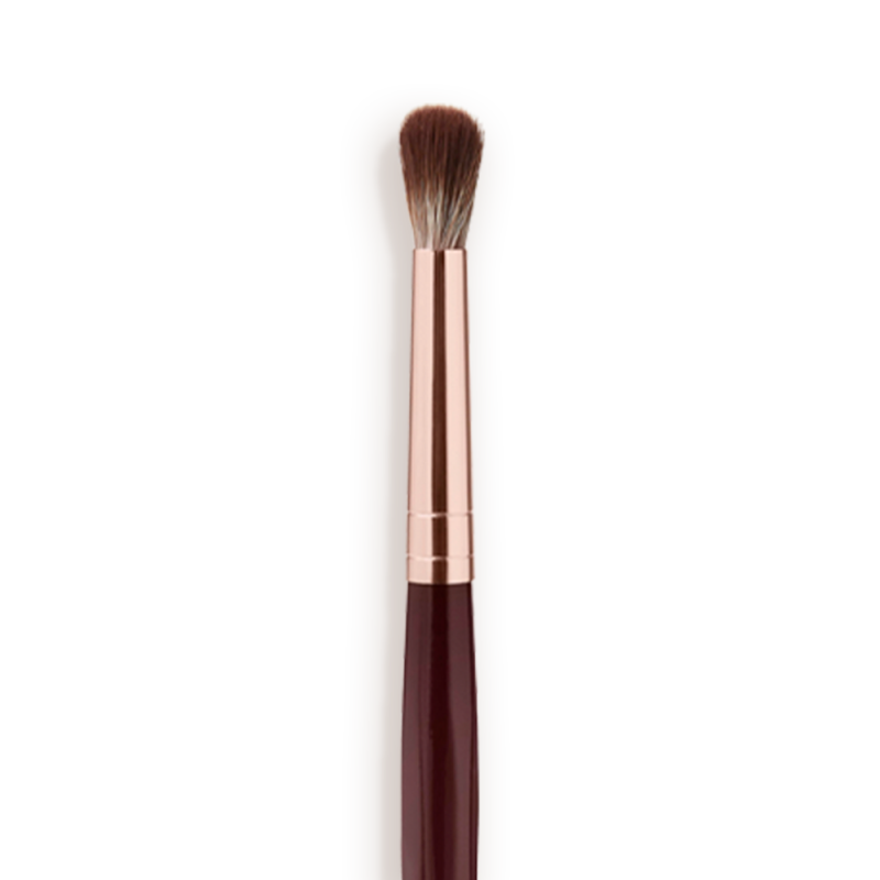 Close-up of an eyeshadow blending brush with soft bristles and a rose-gold and dark crimson handle.