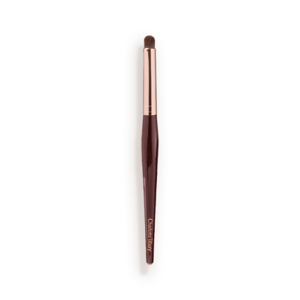An eyeshadow smudging brush with soft bristles and rose gold and dark crimson handle.