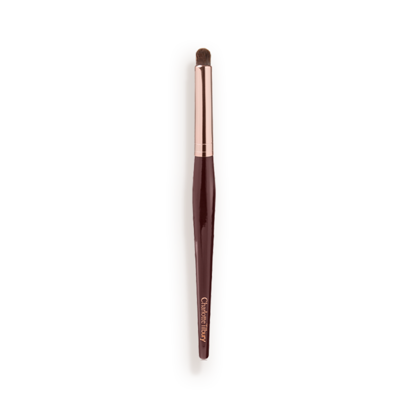 An eyeshadow smudging brush with soft bristles and rose gold and dark crimson handle.