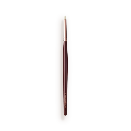 A slim eyeshadow brush with white-coloured bristles with a rose-gold and dark crimson handle. 