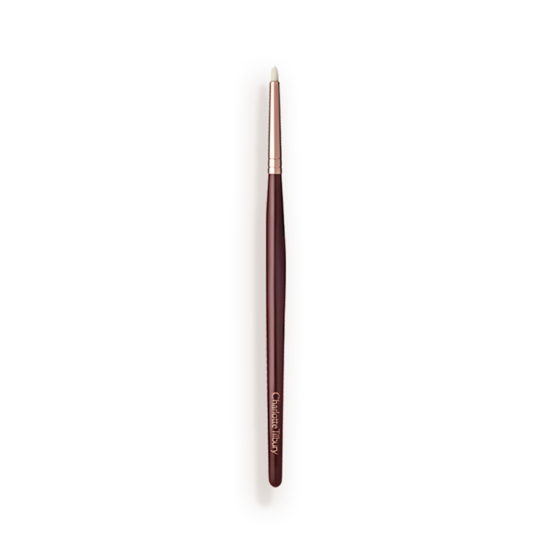 A slim eyeshadow brush with white-coloured bristles with a rose-gold and dark crimson handle.