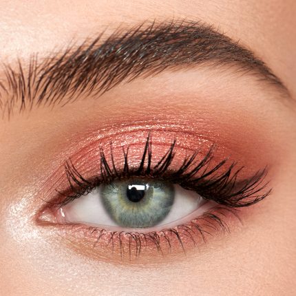 Single-eye close-up of a fair-tone model with blue eyes wearing shimmery rose gold eyeshadow.